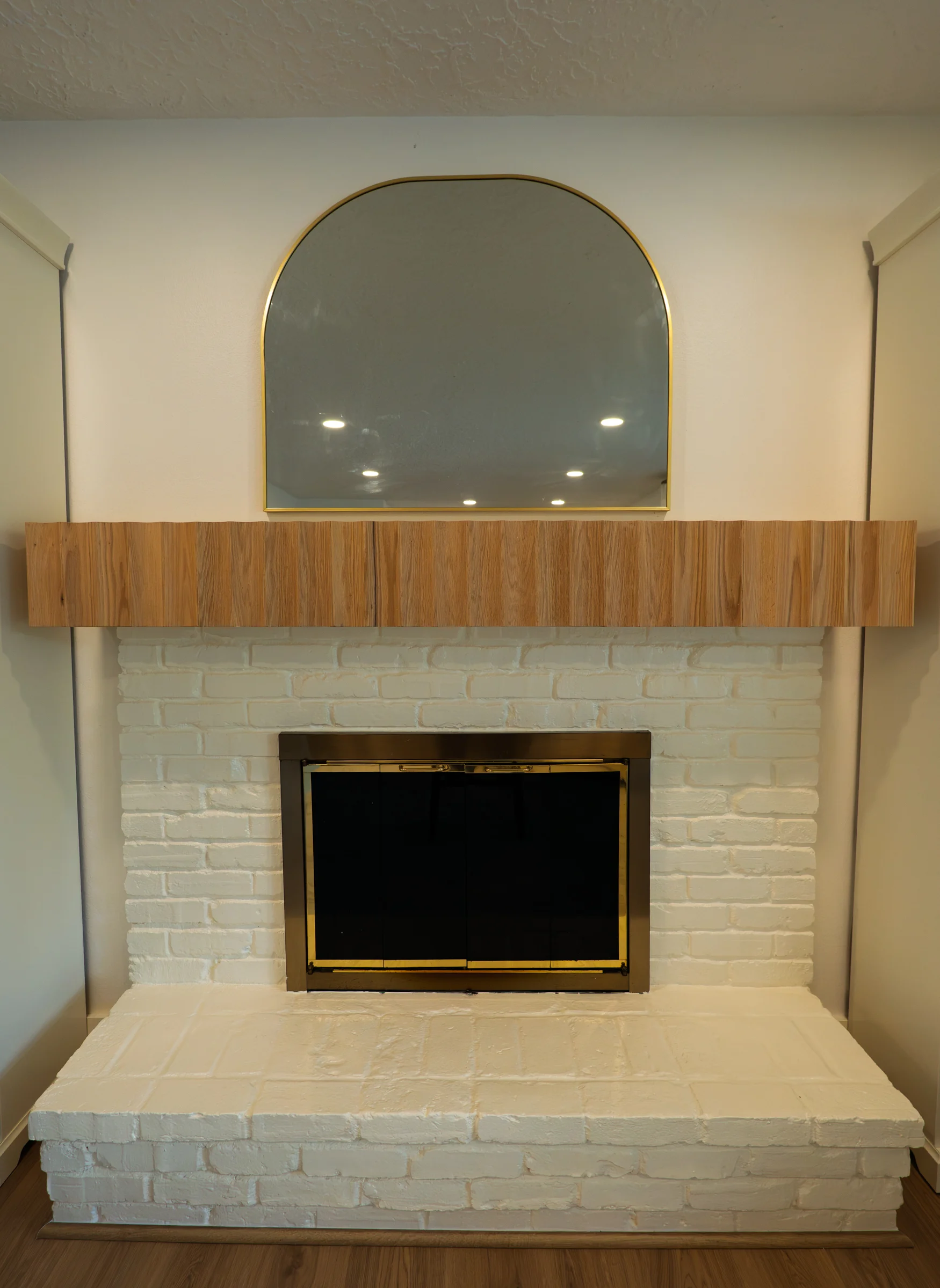Updated fireplace trim with white brick surround, wood mantel, and arched mirror, Portland OR